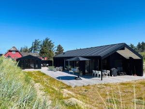 un edificio nero con tavoli e sedie di fronte di BL1489-Blokhus-Paa-Bakken-8-B a Blokhus