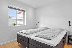 a bed in a white room with a window at BL1520-Blokhus-Klitgaardsvej-3-B in Blokhus