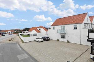 a white house with two cars parked in a parking lot at BL1520-Blokhus-Klitgaardsvej-3-B in Blokhus