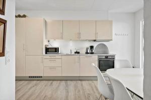 a kitchen with white cabinets and a table and chairs at BL1260-Blokhus-Strandvejen-14-Lejl-9 in Blokhus +19 photos