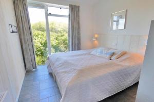 Un dormitorio con una cama grande y una ventana grande. en Beachlife 9, en Callantsoog