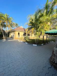 a driveway in front of a house with palm trees at Rhovee Arusha in Arusha