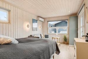 um quarto com uma cama, uma cadeira e janelas em BL709-Blokhus-Kr-Thomsensvej-5 em Blokhus