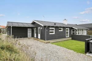 uma casa preta com um relvado à frente em BL709-Blokhus-Kr-Thomsensvej-5 em Blokhus