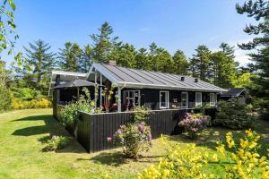 a black house with a fence in a yard at BL1666-Saltum-Vikingebanke-5 in Saltum