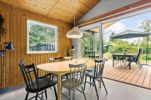 a dining room with a table and chairs on a deck at BL1728-Blokhus-Kaeruldvej-7 in Blokhus +17 photos