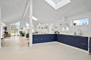 a large kitchen with blue cabinets and a living room at BL1355-Blokhus-Ribergaardsvej-24 in Blokhus