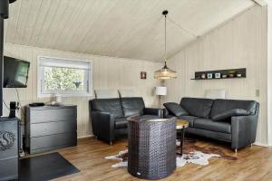 a living room with black leather furniture and a tv at BL1546-Saltum-Stenrev-6 in Saltum