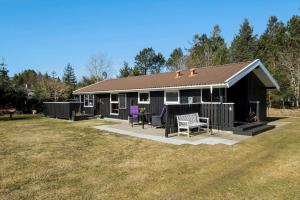 a black house with a patio and chairs in the yard at BL1546-Saltum-Stenrev-6 in Saltum