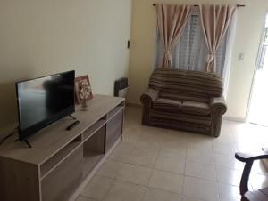 a living room with a flat screen tv and a chair at Duplex Rawson in Gualeguaychú