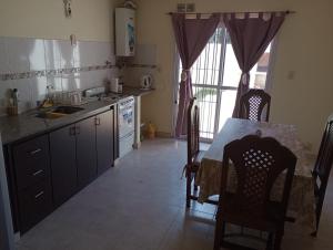 a kitchen with a table and a sink and a table and chairs at Duplex Rawson in Gualeguaychú +2 photos