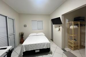 a white bedroom with a bed and a window at Kitnet Studio Apartamento Privativo Jundiaí 06 in Jundiaí