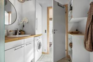 a white kitchen with a sink and a washing machine at BL1458-Blokhus-Lyngmarken-6 in Blokhus +25 photos