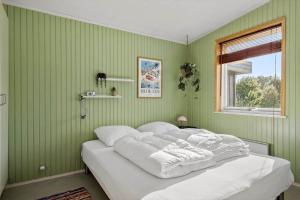 a bedroom with green walls and a bed with white pillows at BL1275-Blokhus-Pirupshvarrevej-17 in Blokhus