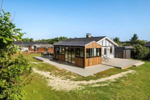 a house with a deck in a yard at BL1275-Blokhus-Pirupshvarrevej-17 in Blokhus