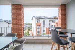 a balcony with tables and chairs and a large window at Ballito Hills 164 in Ballito