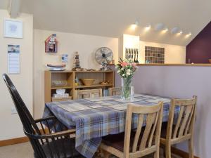 Una mesa de comedor con un jarrón de flores encima. en The Bait Shed, en Filey