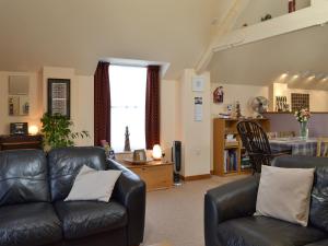 Una sala de estar con un sofá de cuero y una mesa. en The Bait Shed, en Filey