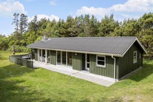 un edificio verde con un portico su un campo di BL433-Blokhus-Raappenmark-8 a Blokhus