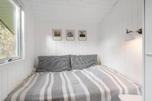 un letto in una camera bianca con una coperta a righe di BL1274-Blokhus-Raappenmark-30 a Blokhus