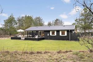 una piccola casa nera con un ampio cortile di BL1274-Blokhus-Raappenmark-30 a Blokhus