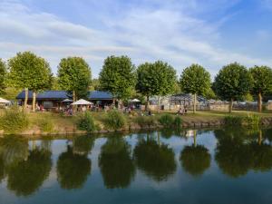 Blick auf einen See mit einem Restaurant im Hintergrund in der Unterkunft Huttopia Baie du Mont Saint Michel in Baguer-Pican + 29 Fotos