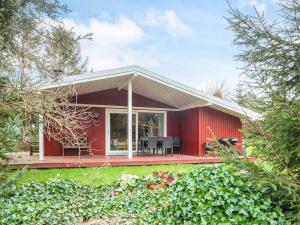 a red house with a deck and chairs in front of it at 6 person holiday home in Fårvang in Fårvang