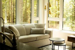 a living room with a couch and two windows at Spa Relaxation Forest & River - Le Marmontin in Sainte-Christine-D'Auvergne +41 photos