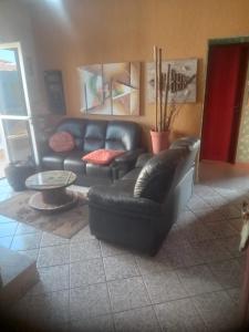a living room with a black leather couch and a table at Apartamento Piúma in Piúma