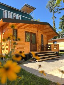 a log cabin with a porch and stairs to it at Solwood Cottage Ureki in Ureki