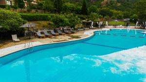 a large blue swimming pool with chairs and umbrellas at Hotel Epavlis in Káto Poróïa