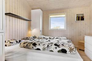 a bedroom with a bed with a black and white comforter at BL819-Blokhus-Pirupshvarrekrogen-2 in Blokhus