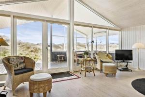 a living room with glass doors and chairs and a television at BL819-Blokhus-Pirupshvarrekrogen-2 in Blokhus