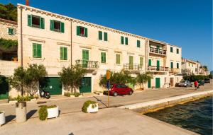 a building with green shuttered windows next to the water at Three-Bedroom Apartment In Povlja in Povlja