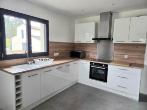 a kitchen with white cabinets and a sink and a window at Le chalet du Petit Ours Brun in Formiguères