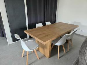 a wooden table with four white chairs around it at Le chalet du Petit Ours Brun in Formiguères +5 photos