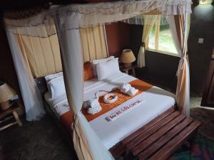 a bedroom with two beds with towels and a bench at Sharp Island Gorilla Lodge, Lake Bunyonyi in Kashasha