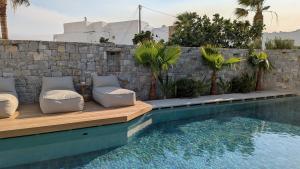 a pool with two lounge chairs next to a stone wall at Nuca Mykonos Hotel in Platis Gialos
