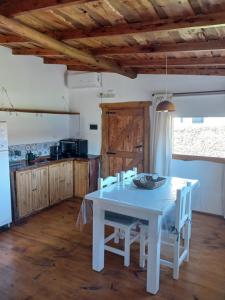 a kitchen with a white table and white chairs at La Cabaña de Sofi in Tandil