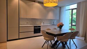 a kitchen with a table and chairs and a kitchen with white cabinets at First Line - Dzintaru prospekts Apartment in Jūrmala