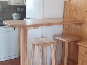 a wooden table in a kitchen with two stools at Chalet Mitoyen Duplex 3 Pièces, 6 Personnes, Résidence Le Hameau du Puy, Superdevoluy - FR-1-504-465 in Superdevoluy