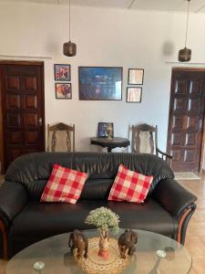 a living room with a black leather couch and a glass table at Ameeila villa in Kandy