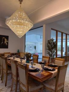 a dining room with a long table and a chandelier at شالية هواك in Al Ḩadd