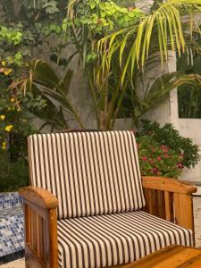 a wooden chair with a striped cushion on a patio at شالية هواك in Al Ḩadd