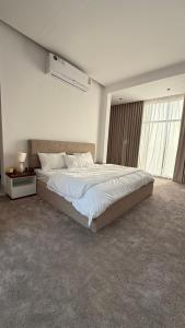 a bedroom with a large bed and a large window at شالية هواك in Al Ḩadd