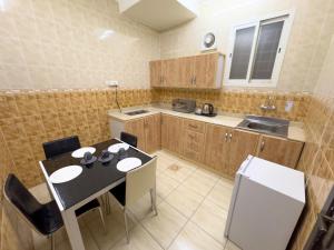 a kitchen with a table and chairs in a kitchen at Masaf apartment in Al Mithnab