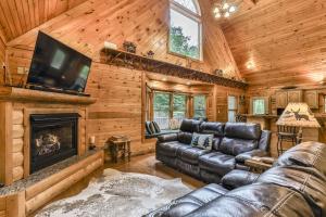 ein Wohnzimmer mit einem Ledersofa und einem Kamin in der Unterkunft DANCING BEARS CABIN - Secluded 3-Bedroom, 3.5-Bath Luxury Cabin with Hot Tub in Mineral Bluff