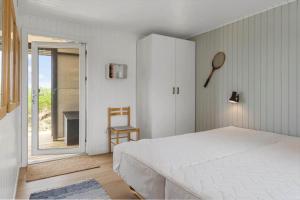 a bedroom with a white bed and a sliding glass door at BL1020-Pandrup-Hunetorp-Klitvej-257 in Pandrup