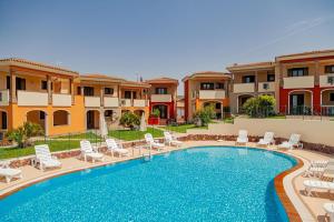a swimming pool with lounge chairs and a resort at Residenza Le Farfalle in Tergu