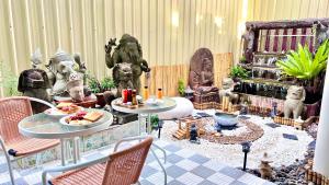 a room with statues and tables with food on them at Baan inta hostel - บ้านอินตาโฮสเทล in Phra Nakhon Si Ayutthaya